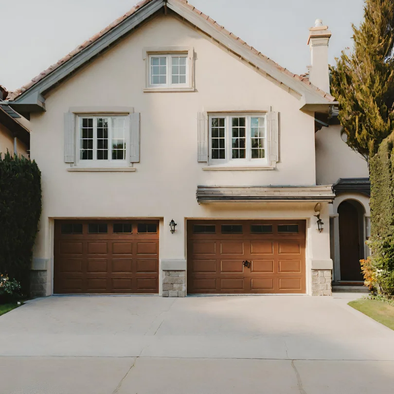 white garage door with small windows on a residential home with a red tiled roof and a paved driveway at dallas